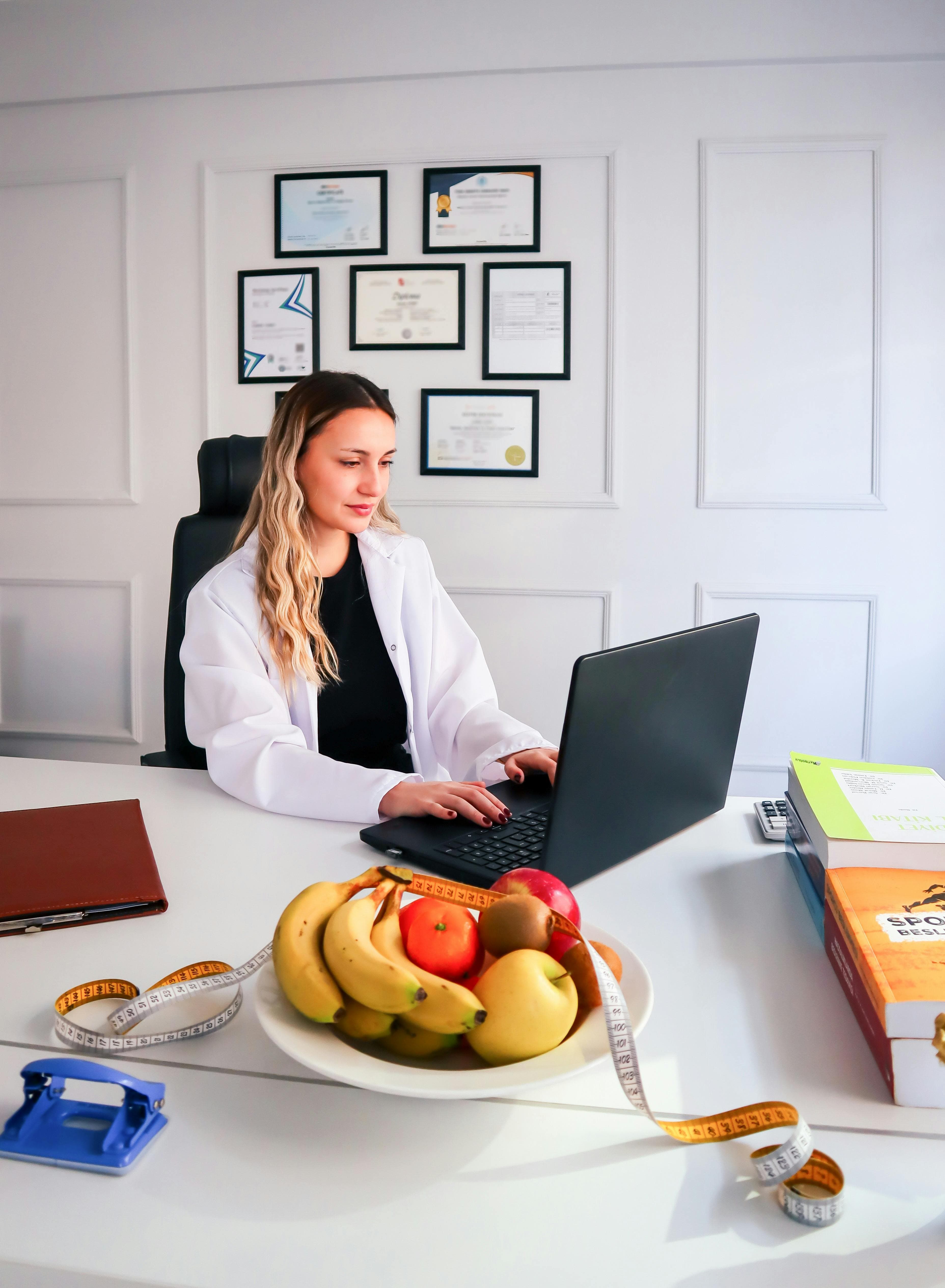 Nutrition specialist coordinating athlete plans using a laptop and food context